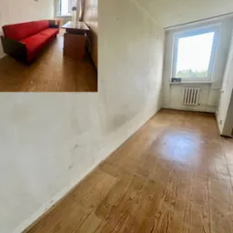 Pokój przed opróżnianiem: czerwona sofa, drewniana podłoga, białe ściany i okno. Część pokoju jest pusta, co kontrastuje z umeblowaną przestrzenią.