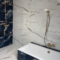 Robert Potoczny - Elegancka łazienka w bieli i granacie z marmurowym wzorem, złota armatura, wanna z czarnym obramowaniem. Nowoczesny design z dbałością o detale.