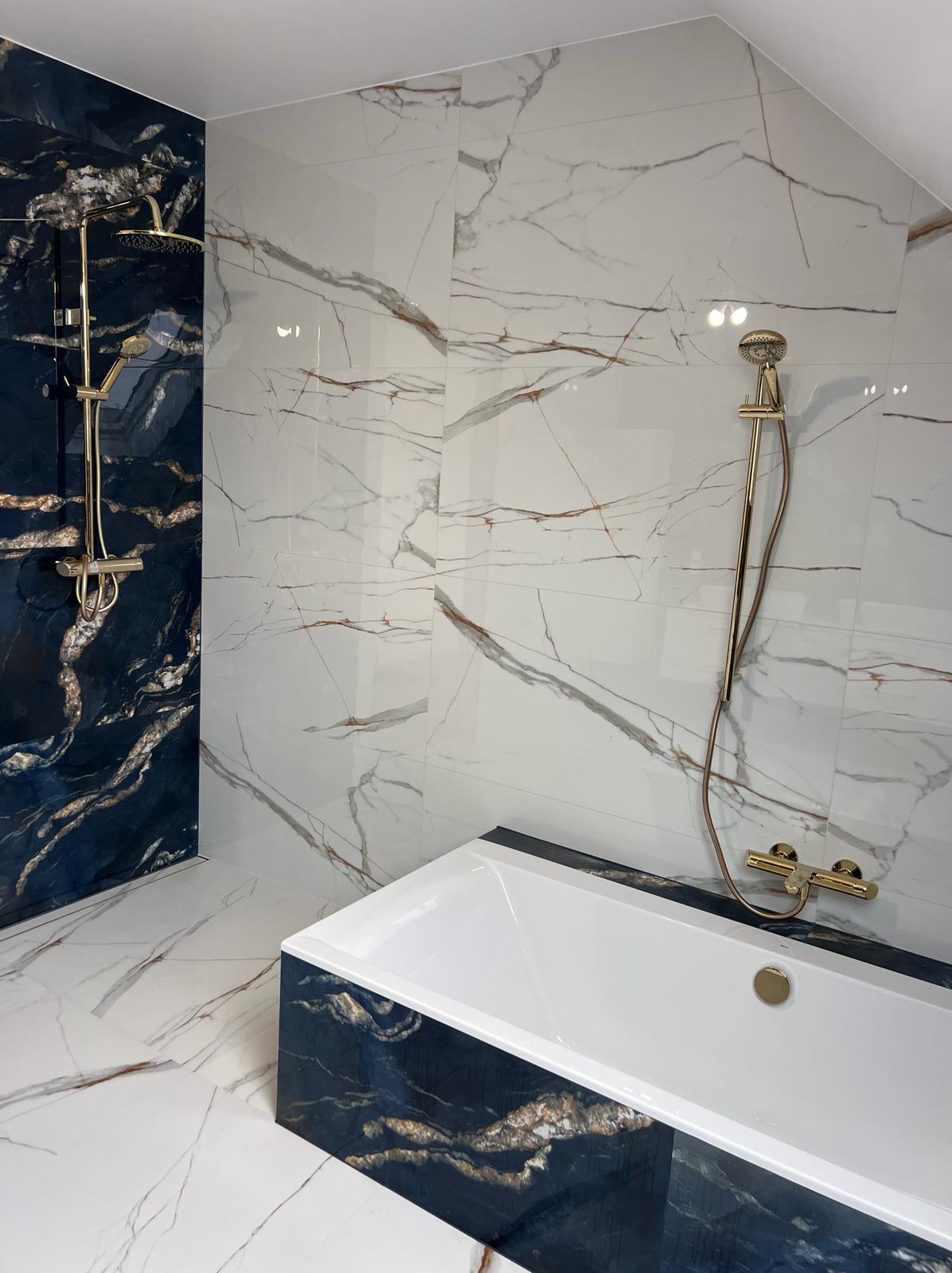 Elegancka łazienka w bieli i granacie z marmurowym wzorem, złota armatura, wanna z czarnym obramowaniem. Nowoczesny design z dbałością o detale.