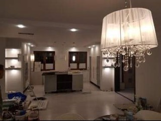 Nowoczesne wykończenie wnętrza w Poznaniu: białe ściany, elegancki żyrandol i meble w trakcie montażu, widok na przestronne pomieszczenie przed finalnym umeblowaniem.