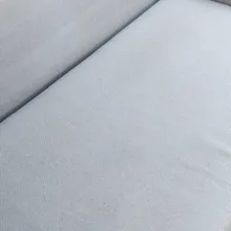 Jasnoszara, czysta kanapa z bliska. Widoczna faktura materiału i delikatne światło. Minimalistyczny design mebla.