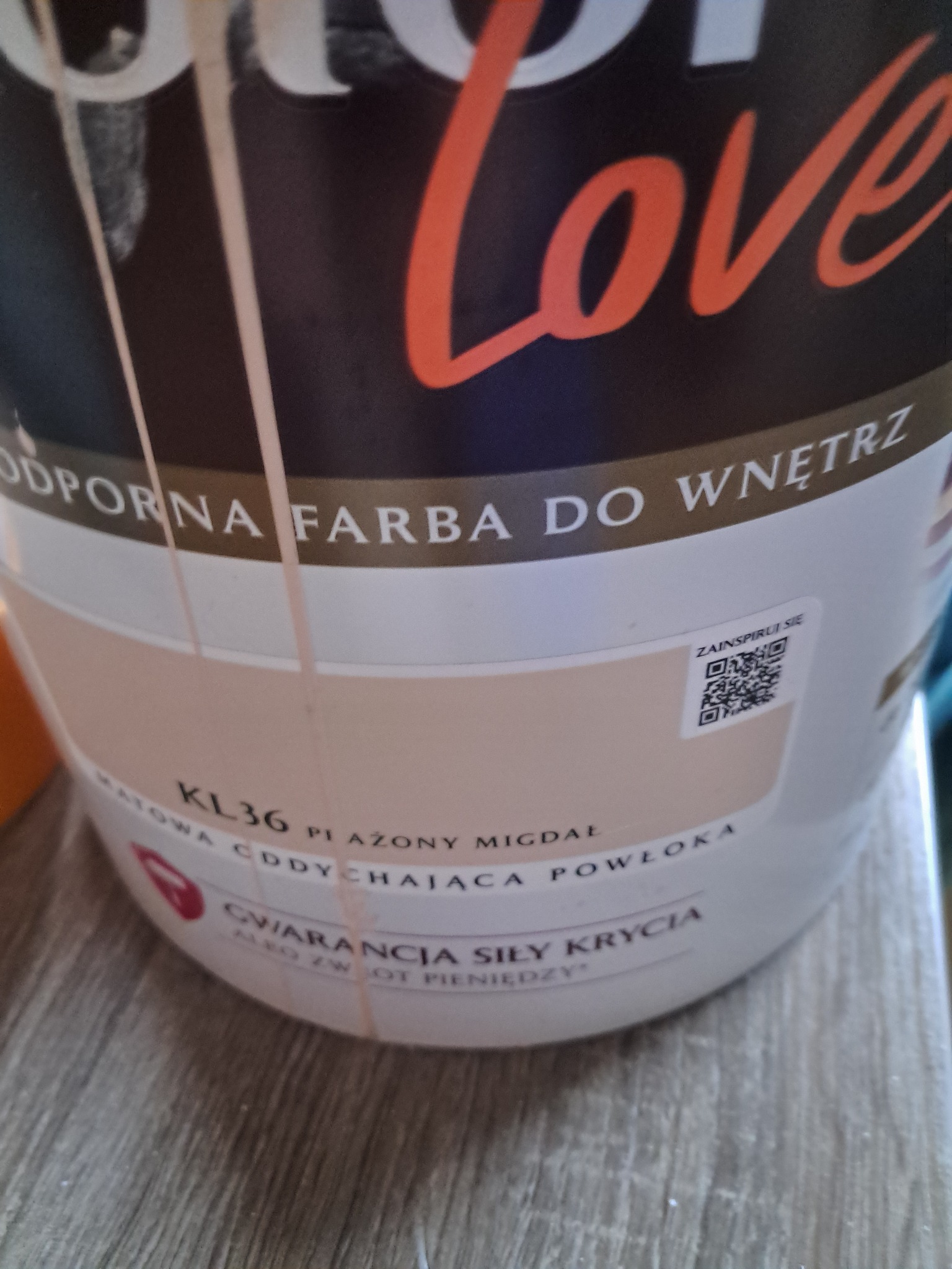 Puszka farby do wnętrz Color Love, odcień KL36 Plażony Migdał. Matowa, oddychająca powłoka, gwarancja siły krycia. Widoczne zacieki farby na puszce.