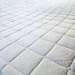 KRAKÓW TOP CLEAN IGOR GOGUNSKYI - Wypełniony, biały materac z pikowaniem w romby, ukazujący czystą powierzchnię po praniu. Widoczne delikatne wzory i tekstura materiału.