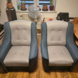 KRAKÓW TOP CLEAN IGOR GOGUNSKYI - Dwa identyczne fotele tapicerowane w odcieniach szarości i błękitu, ustawione obok siebie na drewnianej podłodze, z roślinami w tle na parapecie okiennym.