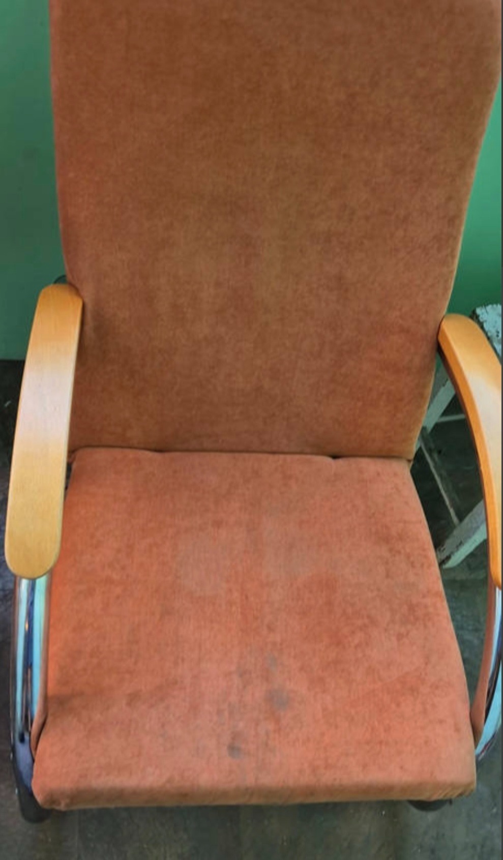 Pomarańczowe krzesło biurowe z drewnianymi podłokietnikami, widoczne plamy na siedzisku, sugerujące potrzebę prania tapicerki.