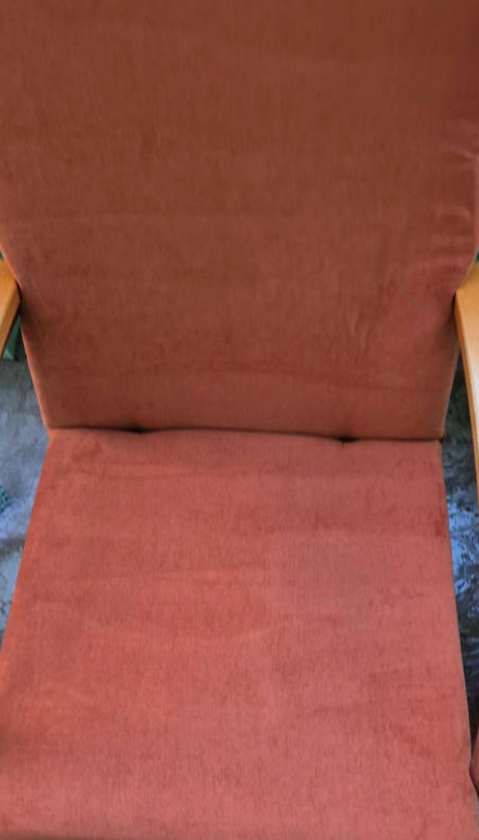 Pomarańczowy fotel z drewnianymi podłokietnikami, widok z góry. Widoczne ślady użytkowania na tapicerce, sugerujące potrzebę odświeżenia.