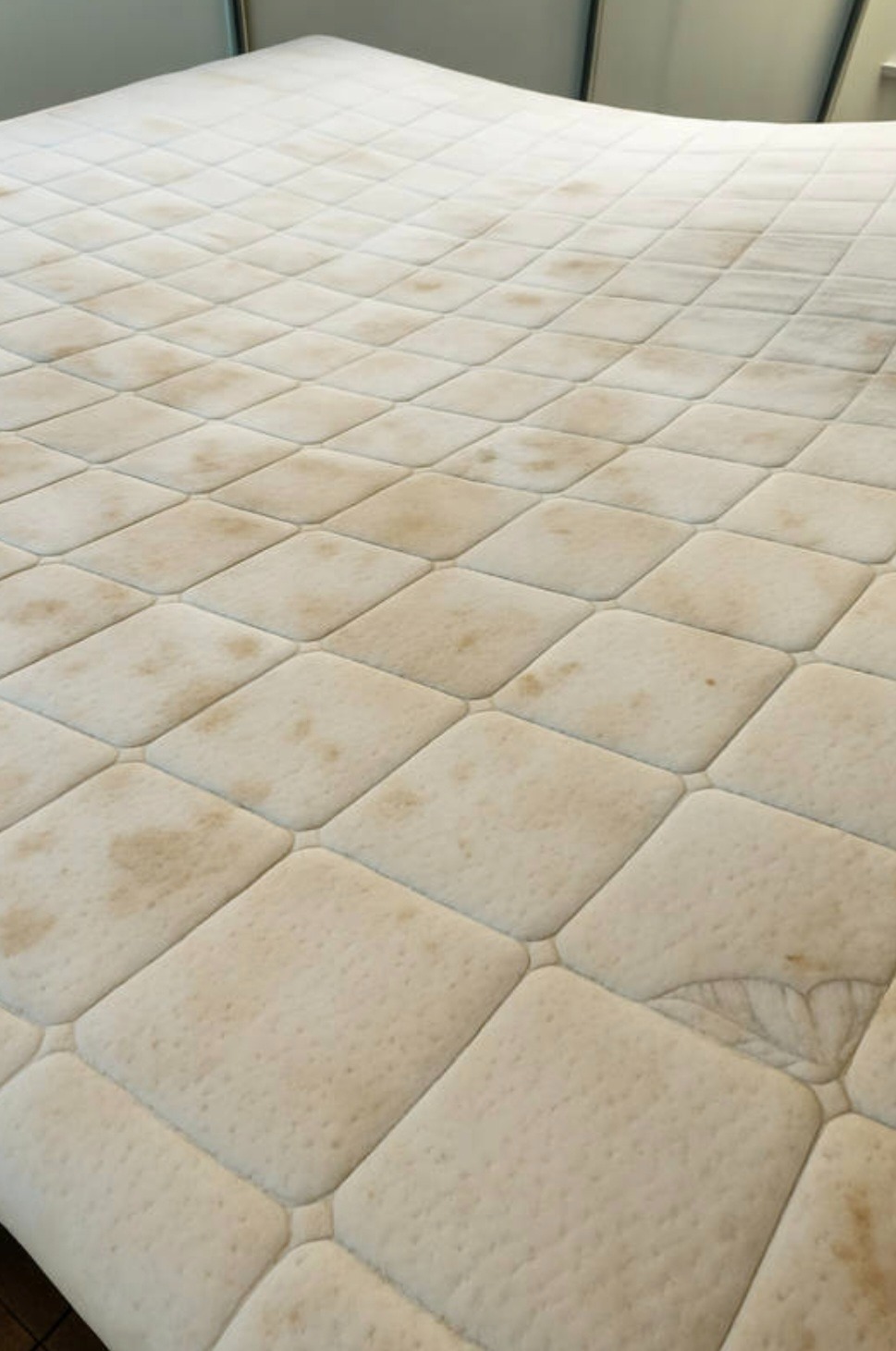 Brudny materac z widocznymi plamami i zabrudzeniami na całej powierzchni, ukazujący potrzebę czyszczenia.