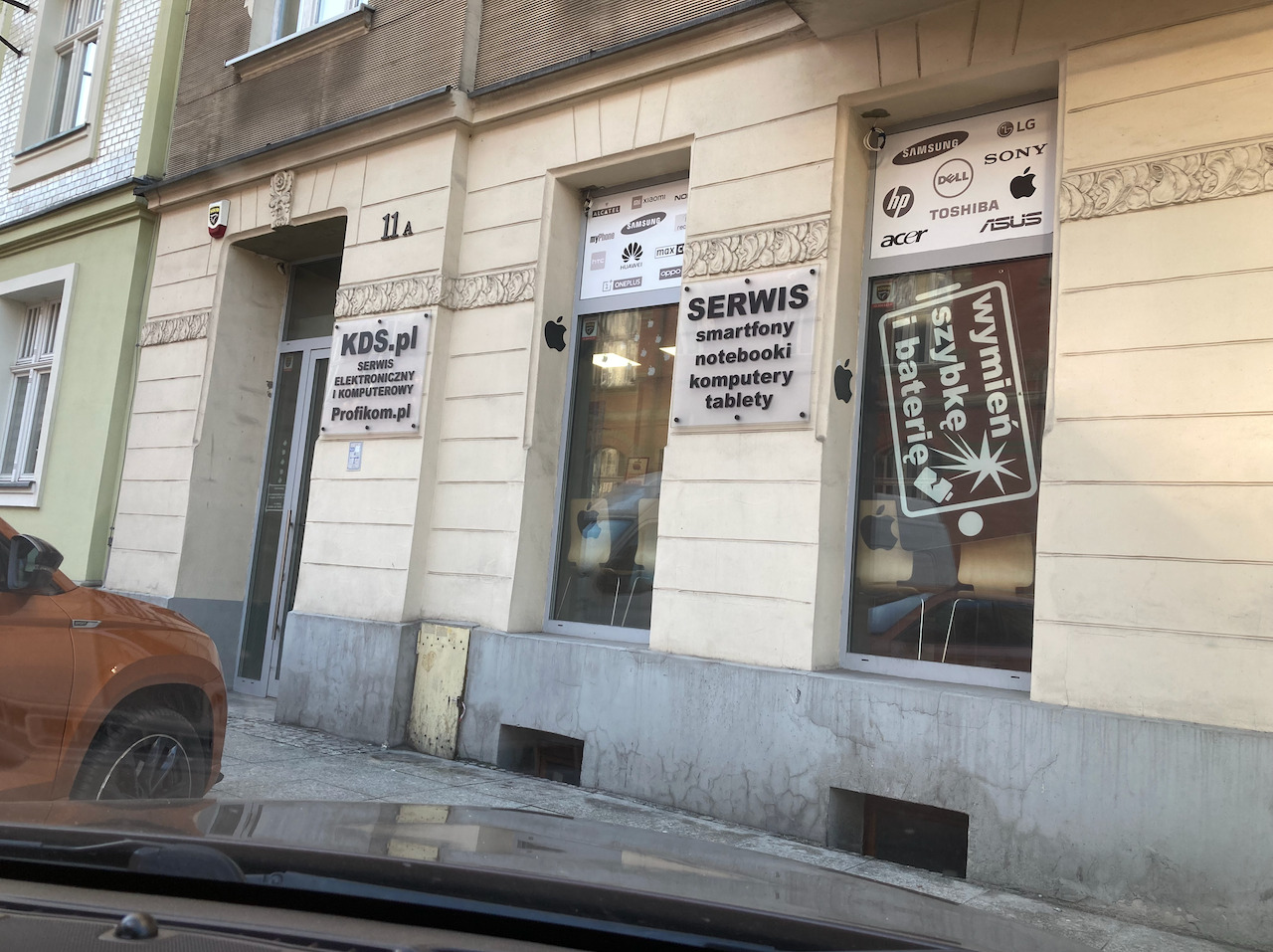 Serwis elektroniki KDS.pl w Katowicach oferuje naprawę smartfonów, notebooków, komputerów i tabletów. Szyldy z logo producentów na witrynie.