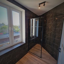 Aproxaa - Nowoczesna łazienka z kabiną typu walk-in, wykończona płytkami imitującymi marmur w ciemnej tonacji i drewnopodobną podłogą. Widoczne okno z widokiem na zewnątrz.