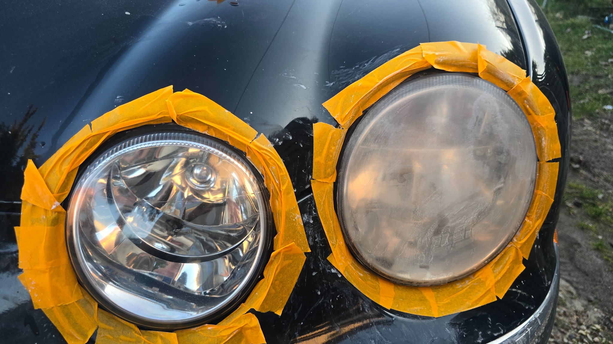 Reflektor samochodowy przed i po renowacji, zabezpieczony taśmą malarską. Widoczna różnica w przejrzystości szkła.