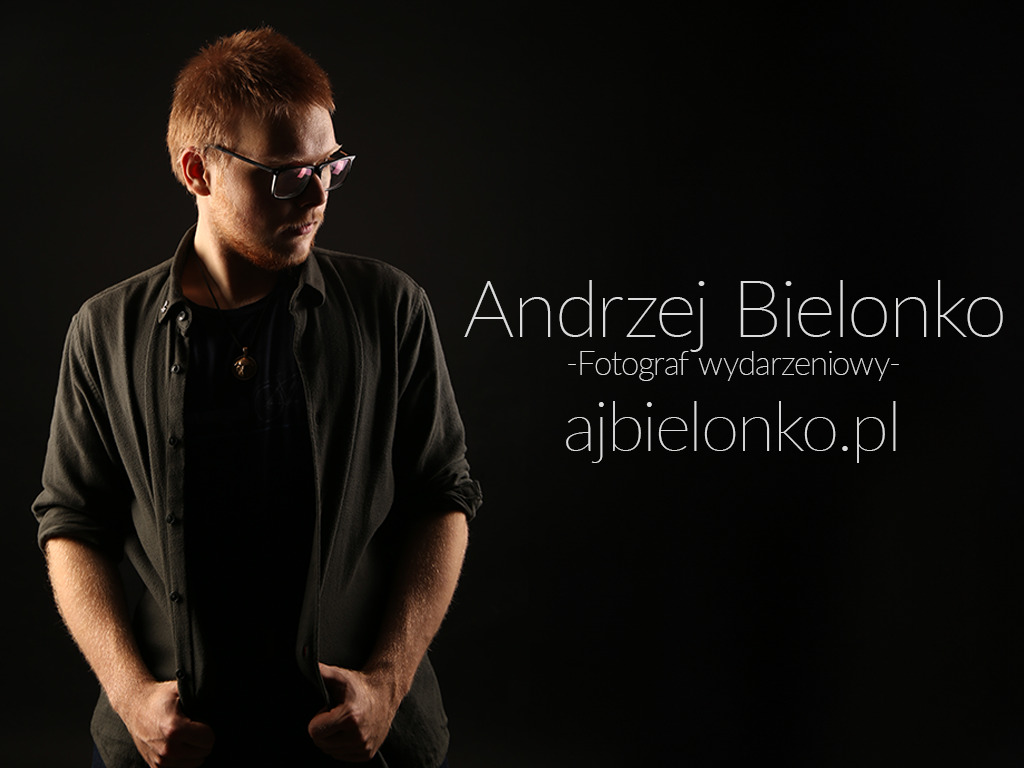 Studyjny portret mężczyzny w okularach, z rudymi włosami, w rozpiętej koszuli na czarnym tle. Widoczny napis 'Andrzej Bielonko - Fotograf wydarzeniowy - ajbielonko.pl'.