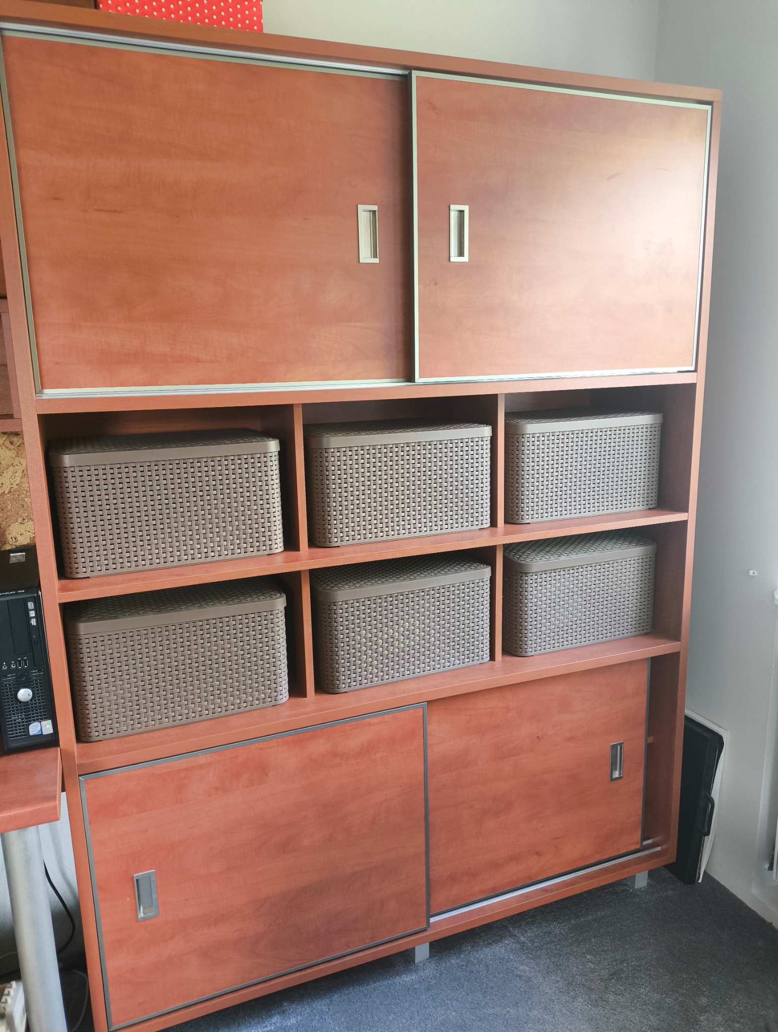 Regał z przesuwnymi drzwiami i półkami z koszami w Koszalinie. Mebel z drewna w odcieniach brązu, widoczne detale wykończenia i metalowe uchwyty.