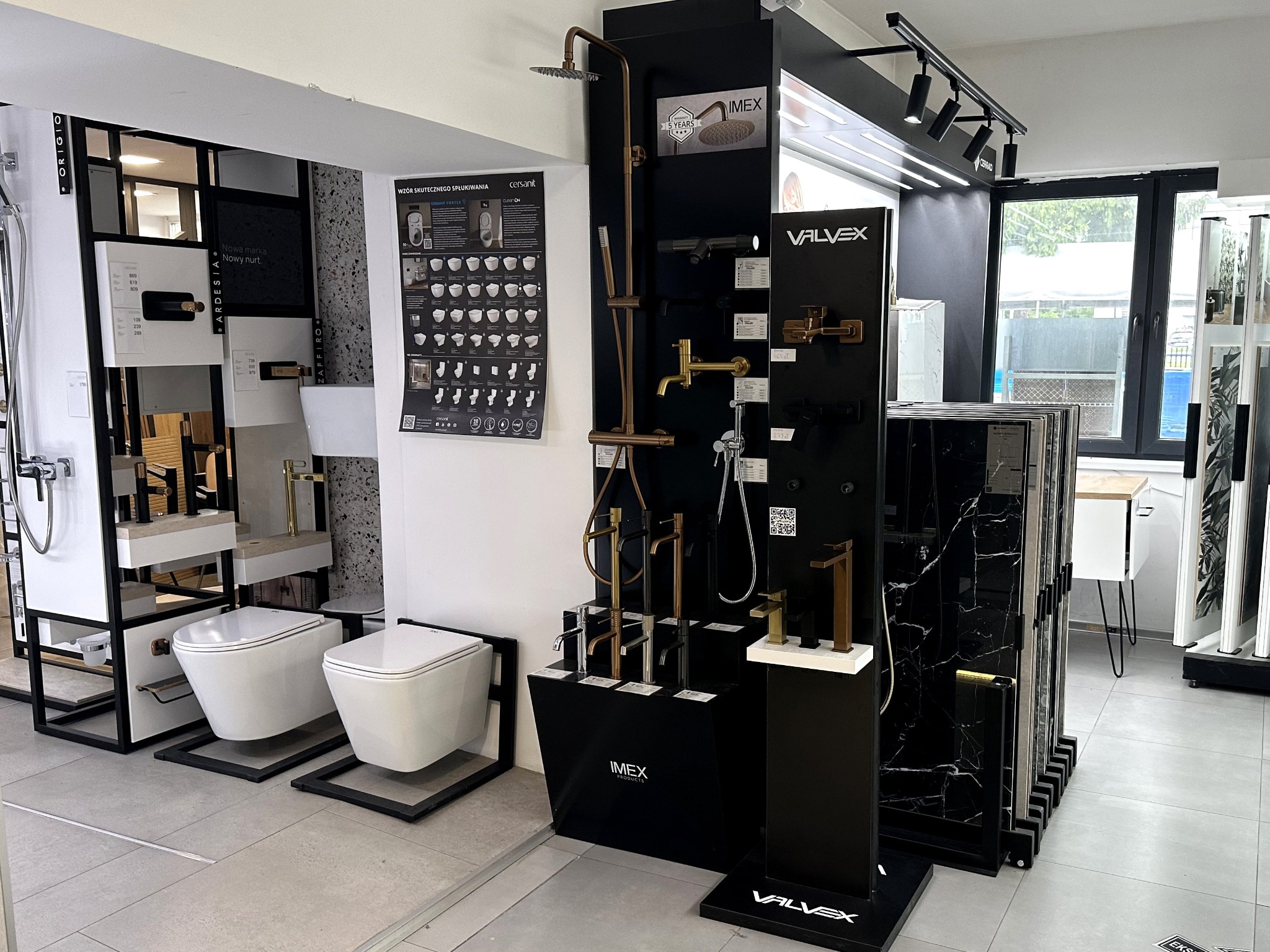 Ekspozycja elementów wyposażenia łazienki: toalety, baterie, panele ścienne. Prezentacja produktów marek Imex i Valvex w salonie. Oświetlenie punktowe.