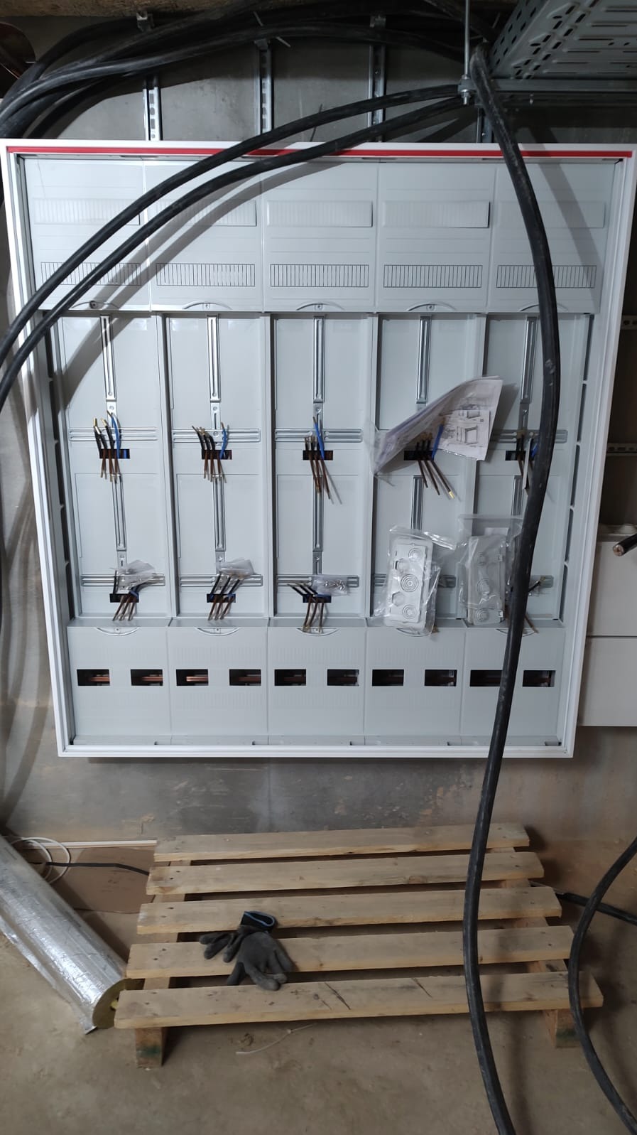 Rozdzielnica elektryczna w trakcie montażu w Kostrzynie nad Odrą. Widoczne przewody, elementy montażowe i skrzynka z modułami. Etap prac instalacyjnych.