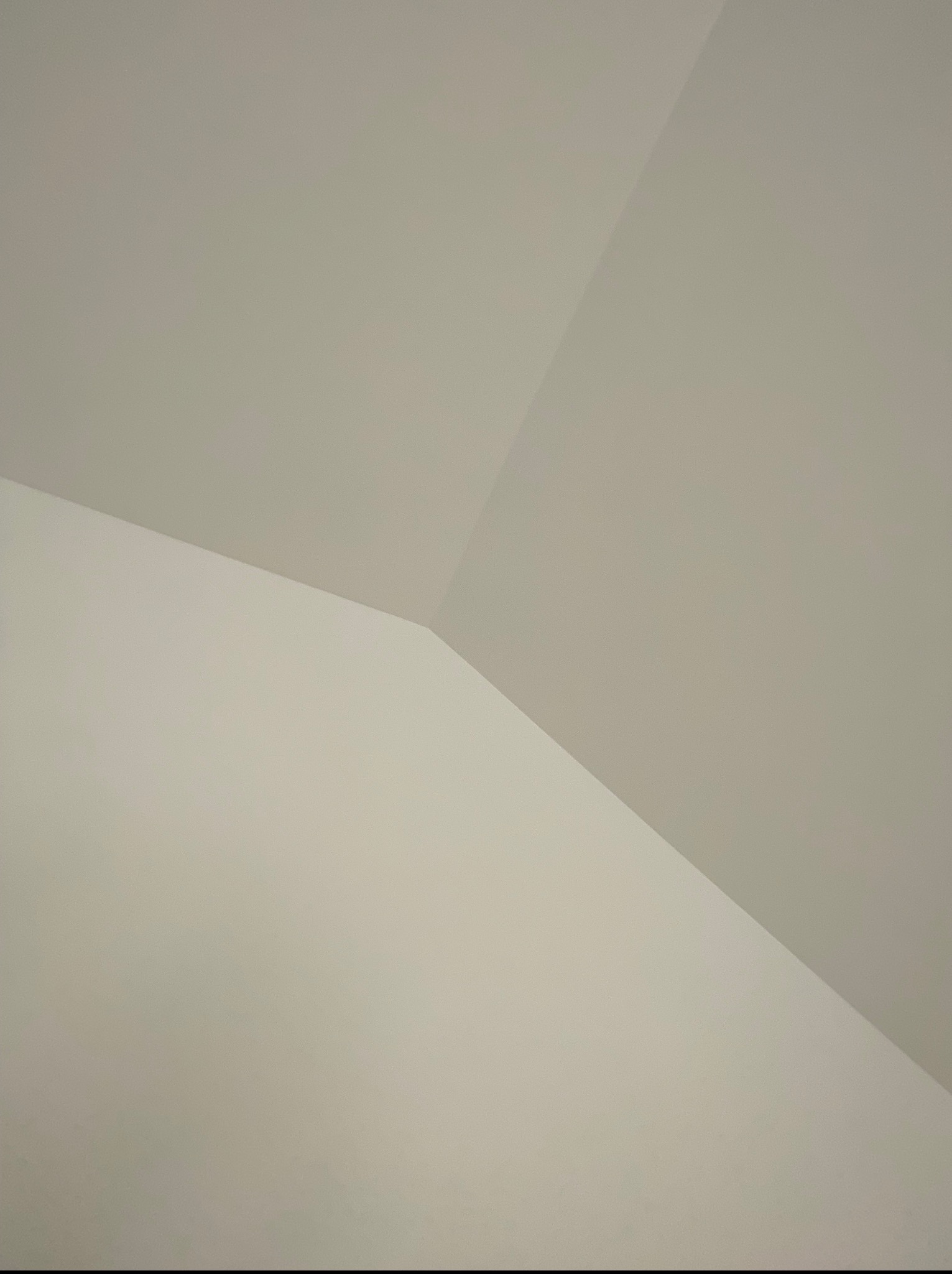 Świeżo pomalowany sufit w odcieniach beżu, ukazujący geometryczne przejścia między ścianami. Minimalistyczne ujęcie z bliska.