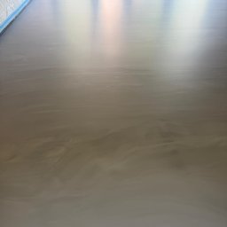 LuxFloors Arkadiusz Tomaszewski - Błyszcząca, beżowo-szara posadzka z efektem chmur, świeżo wylana, zabezpieczona folią przy ścianach. Widoczne odbicia światła.