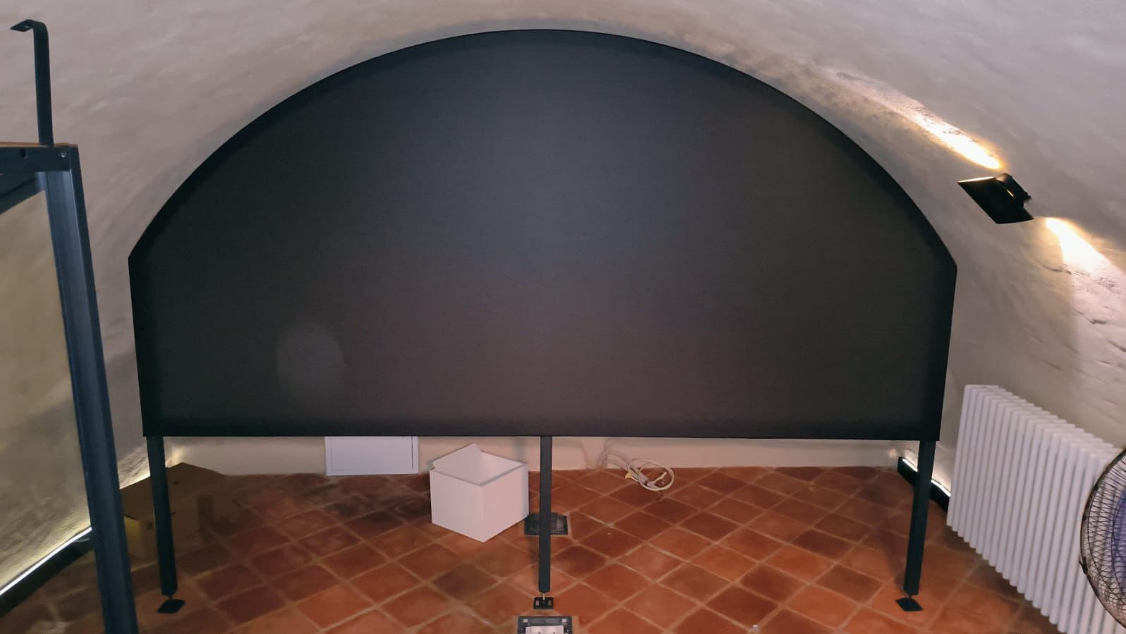 Metalowa konstrukcja z ekranem w piwnicy w Mokrsku. Elementy spawane, widoczna ceglana podłoga i łukowe sklepienie.