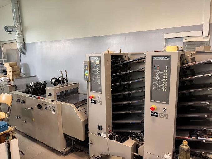Profesjonalna maszyna introligatorska Stahlfolder MC-80 i Horizon SPF-20 w hali drukarni. Widoczny panel sterowania i podajniki. Elementy wykończeniowe.