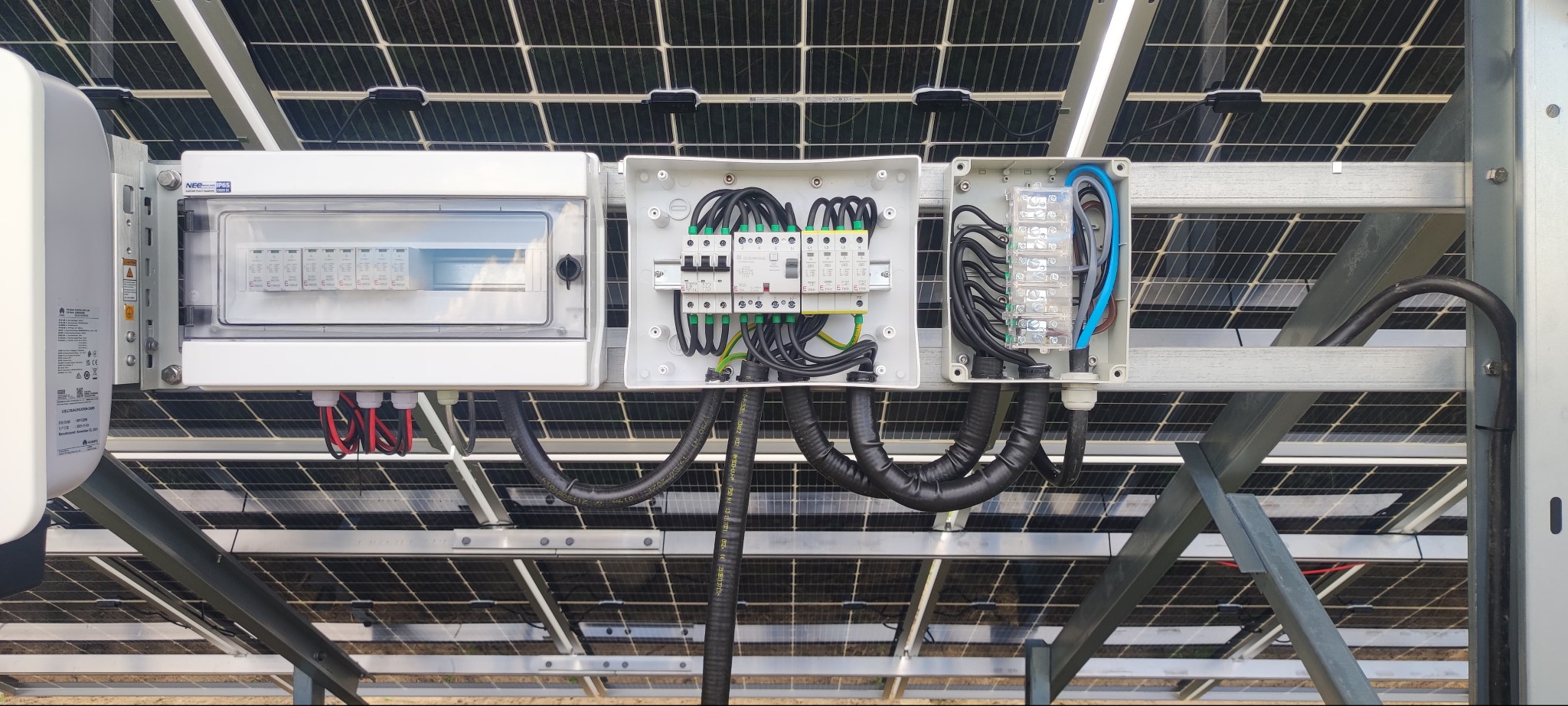 Instalacja elektryczna w skrzynkach pod panelami słonecznymi. Widoczne kable, bezpieczniki i inne elementy osprzętu elektrycznego. Estetyczne i profesjonalne wykonanie.