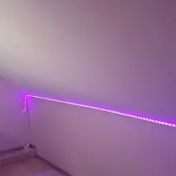 Pokój na poddaszu z różową ścianą i oświetleniem LED, biurko z oknem i krzesłem. Nietypowe oświetlenie nadaje pomieszczeniu nowoczesny charakter.