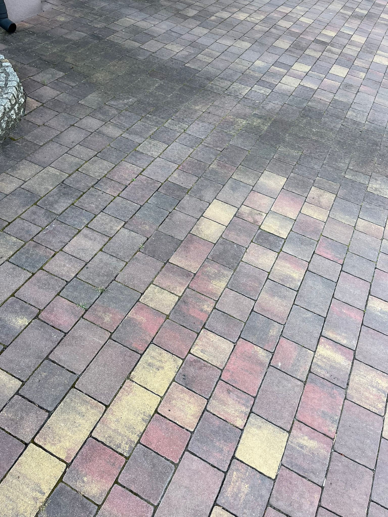 Wielokolorowa kostka brukowa: część wyczyszczona, część zabrudzona. Widoczne różnice w kolorze i stopniu zabrudzenia. Perspektywa z góry.