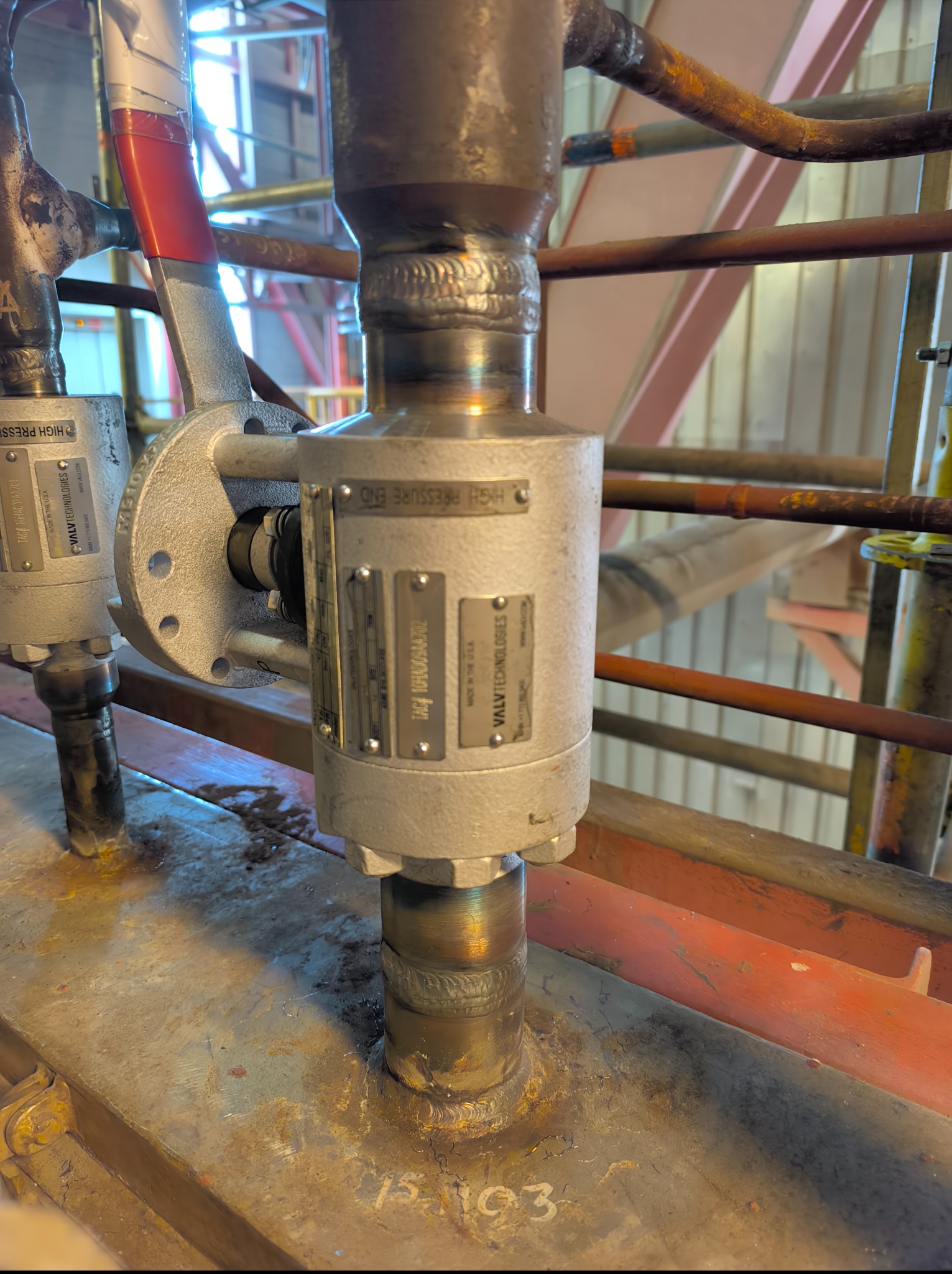 Detale spawanych rur i zaworów przemysłowych z tabliczkami informacyjnymi, ukazujące precyzję wykonania i dbałość o szczegóły w instalacji.