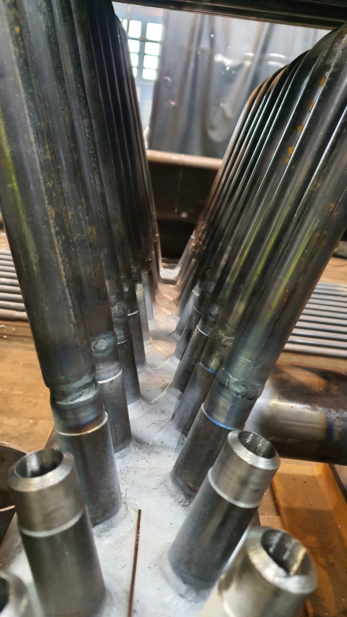 Spoina łącząca rury w konstrukcji metalowej, widoczne ślady spawania i szlifowania. Detal z bliska ukazuje precyzję łączeń i solidność wykonania.