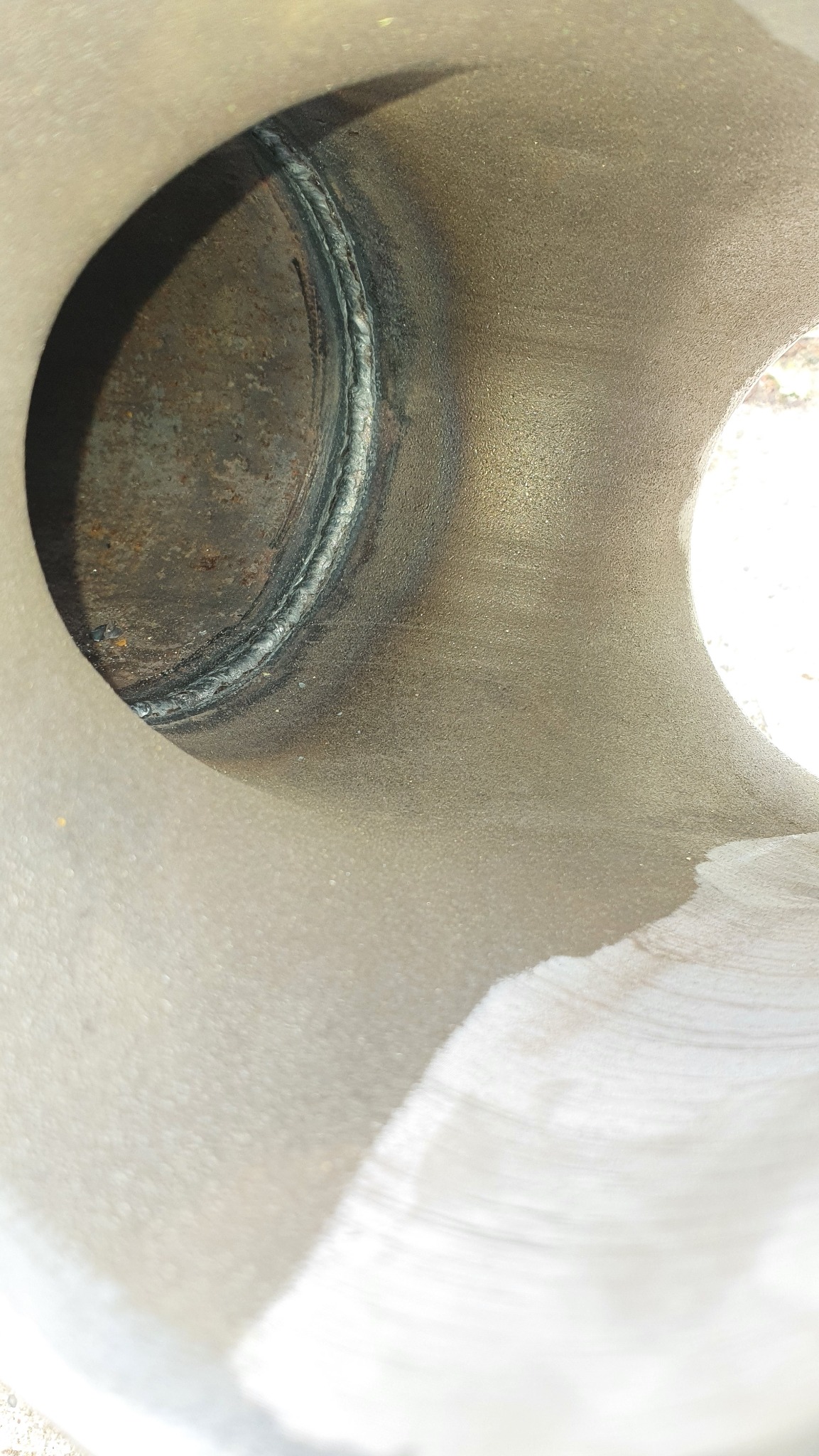 Wnętrze metalowej rury z widocznym, świeżo wykonanym spoiwem. Spaw na okręgu, widoczna faktura metalu i ślady obróbki. Oświetlenie naturalne.