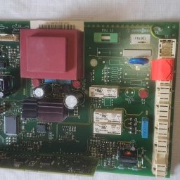 Alex Crisard - Płyta główna pieca gazowego Viessmann z widocznymi elementami elektronicznymi, takimi jak transformator, kondensatory i przekaźniki. Widoczne oznaczenia modelu i parametry.