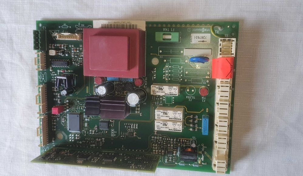 Płyta główna pieca gazowego Viessmann z widocznymi elementami elektronicznymi, takimi jak transformator, kondensatory i przekaźniki. Widoczne oznaczenia modelu i parametry.