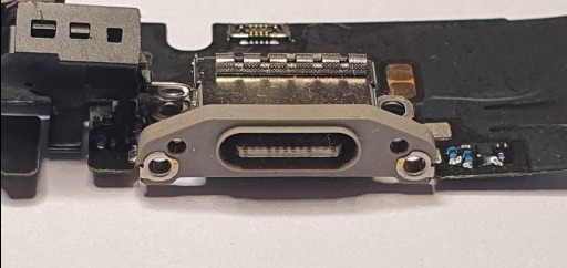 Zbliżenie na port USB-C na płycie urządzenia elektronicznego. Widoczne ślady lutowania i elementy elektroniczne. Detaliczna prezentacja naprawionego gniazda.