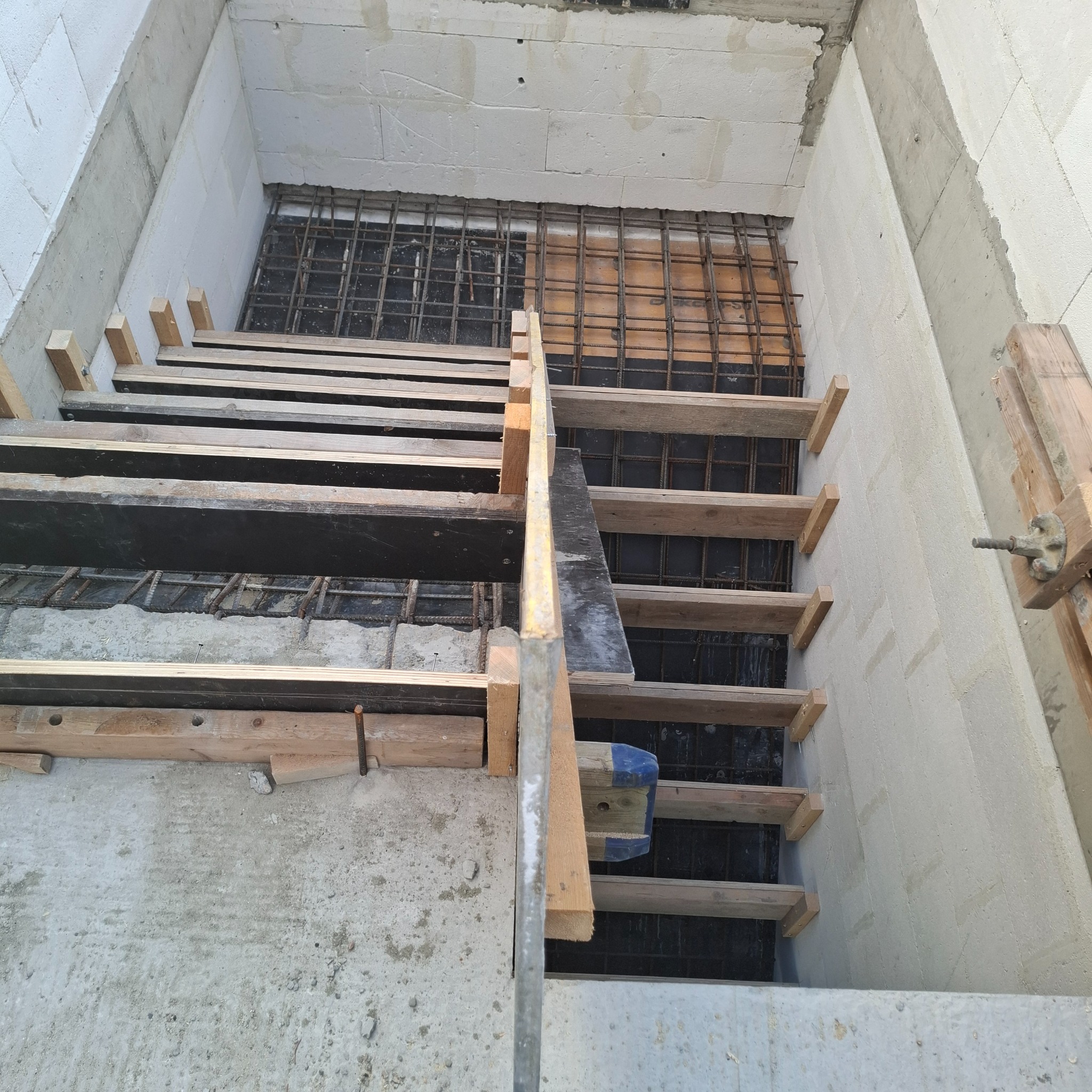 Zbrojenie schodów w szalunku z desek, widok z góry. Elementy konstrukcyjne z betonu komórkowego. Etap budowy domu.