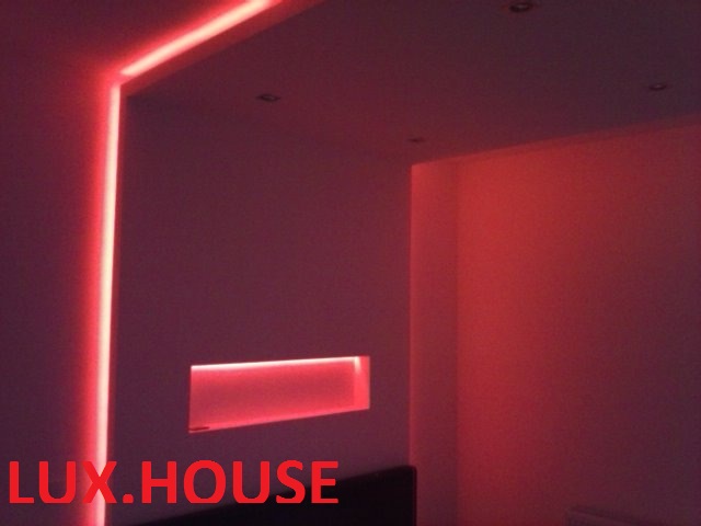 Nowoczesne wnętrze z podświetleniem LED w kolorze czerwonym, zabudowa sufitowa i wnęka ścienna z oświetleniem, widoczne logo firmy LUX.HOUSE.