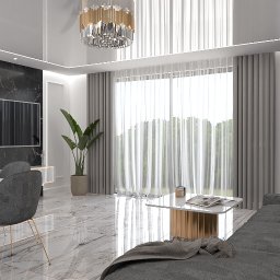 M2 ARCHITEKCI - Elegancki salon z marmurową ścianą, telewizorem, stołem jadalnym z owocami, szarą sofą i rośliną doniczkową. Nowoczesne oświetlenie.