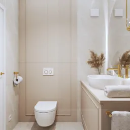 Elegancka łazienka w beżach: wisząca toaleta, umywalka na blacie, okrągłe lustro z oświetleniem. Minimalistyczny design z akcentami złota i marmuru.