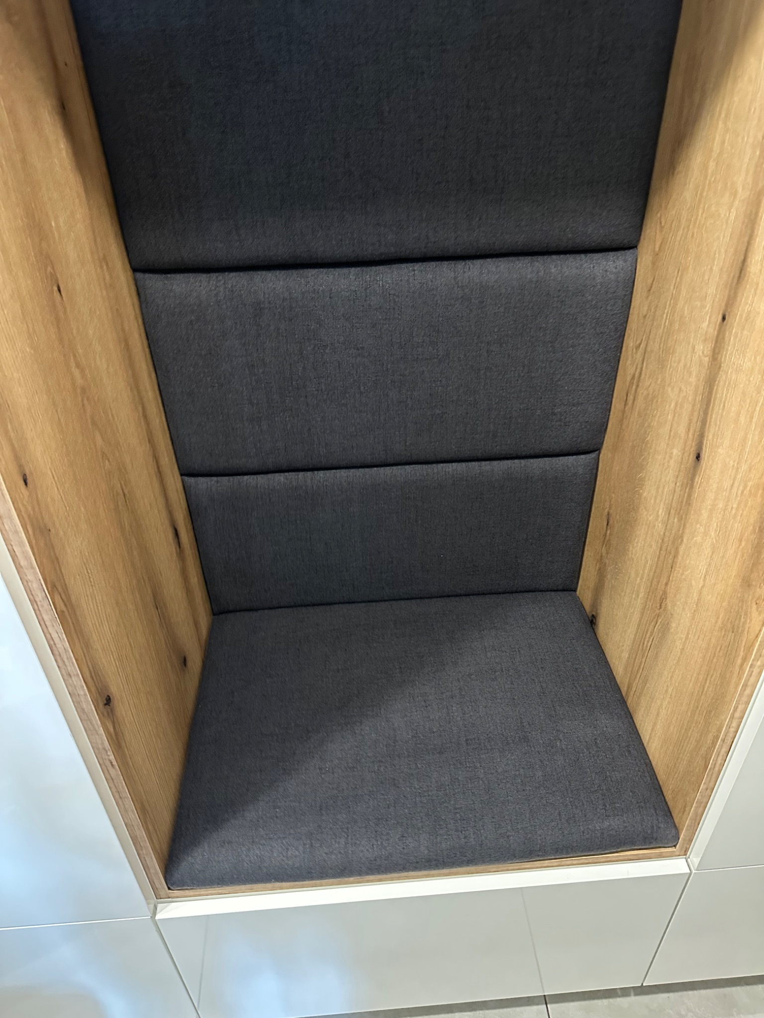 Tapicerowana wnęka z drewnianą obudową i szarą tapicerką. Widok z góry ukazuje siedzisko i oparcie z podziałem na segmenty.