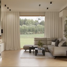 Proli Design Oliwia Pietras - Jasne wnętrze salonu z widokiem na zieleń za oknem. Beżowa sofa narożna, dwa stoliki kawowe i duża roślina doniczkowa tworzą przytulną przestrzeń.