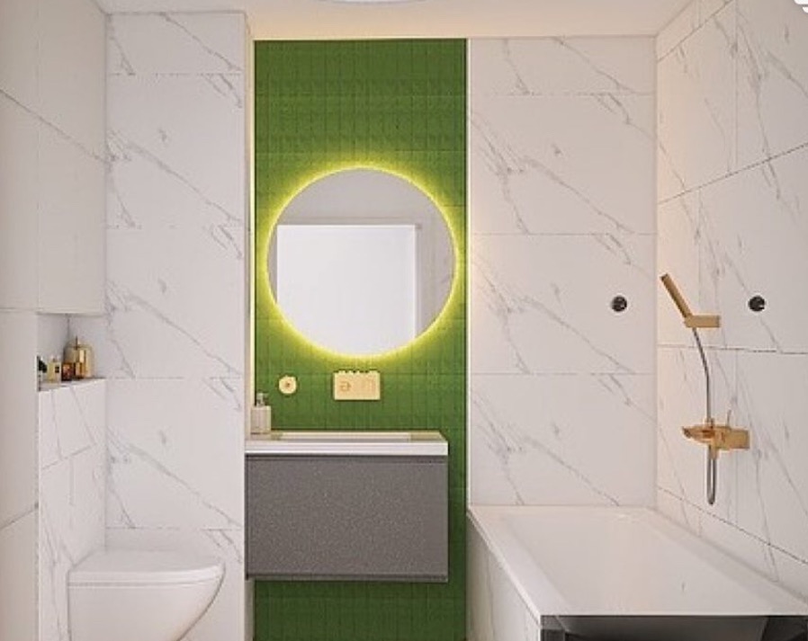 Nowoczesna łazienka z białymi marmurkowymi płytkami, zieloną ścianą z okrągłym lustrem z podświetleniem LED i minimalistyczną armaturą w odcieniach złota.
