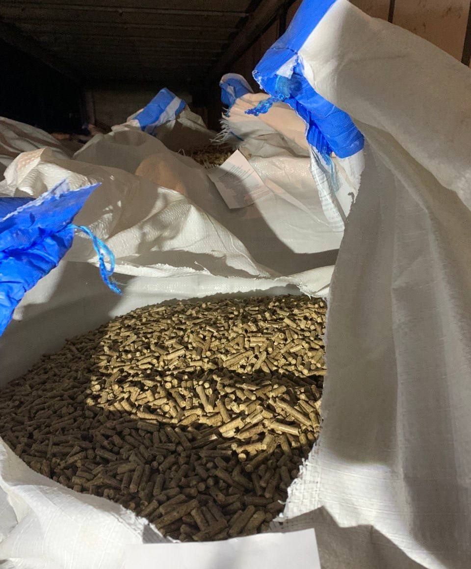 Pellet drzewny w workach typu big bag, z niebieskimi akcentami, w magazynie. Widok z góry na wypełniony worek z bliska. Delikatne oświetlenie.