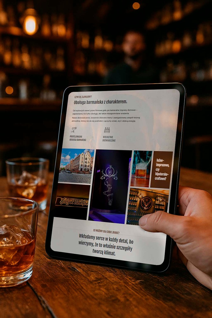 Prezentacja oferty barmańskiej na tablecie trzymanym w dłoni, z drinkiem w szklance na drewnianym blacie. W tle bar z rozmytą postacią.