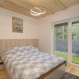 JARO-INVESTMENT - Jasna sypialnia z drewnianym sufitem i przesuwnymi drzwiami balkonowymi. Beżowe wezgłowie łóżka i geometryczny wzór na pościeli. Nowoczesna lampa sufitowa.