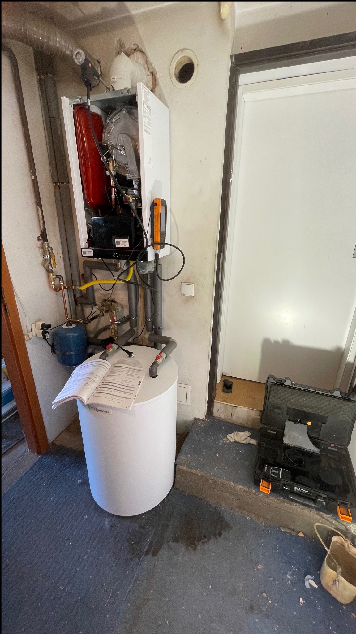 Zamontowany piec gazowy Viessmann z podłączonymi instalacjami. Na zbiorniku leży otwarta instrukcja. Obok skrzynka z narzędziami.