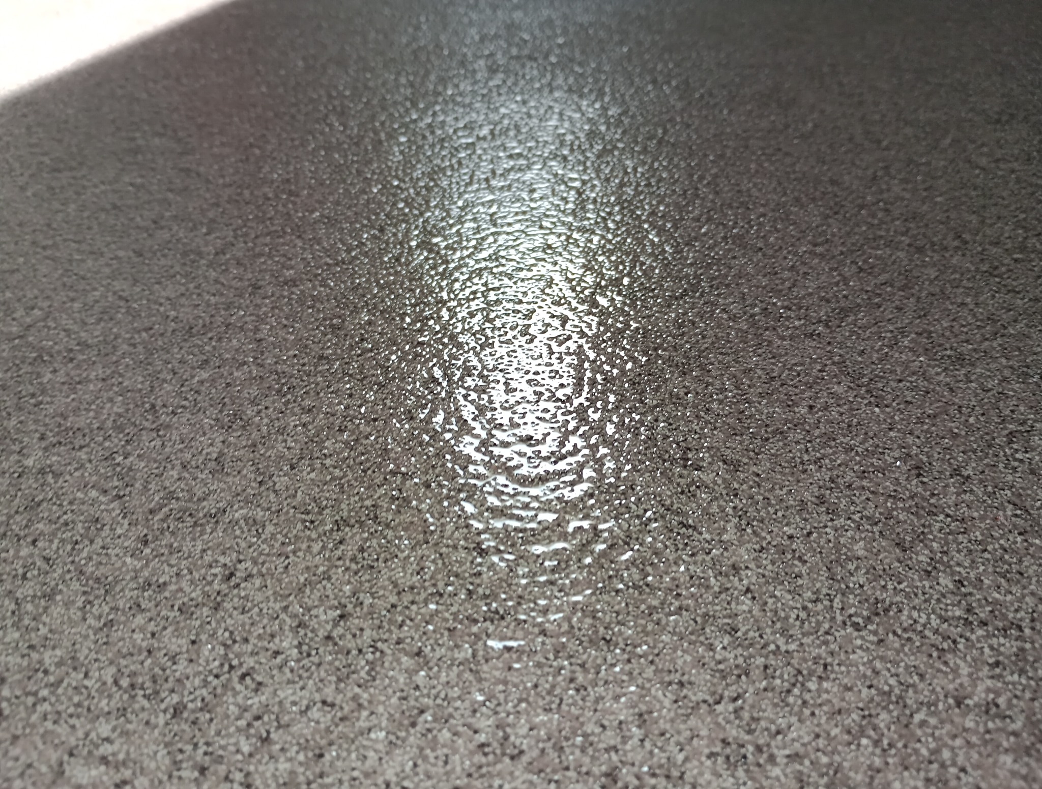 Błyszcząca, szara posadzka żywiczna z wyraźną fakturą i refleksami światła, ukazująca gładką i jednolitą powierzchnię.