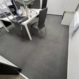 CosmoClean - Biuro po sprzątaniu: szary dywan, białe meble, krzesła na stołach. Porządek w minimalistycznym stylu, gotowe do pracy. Widok z góry.