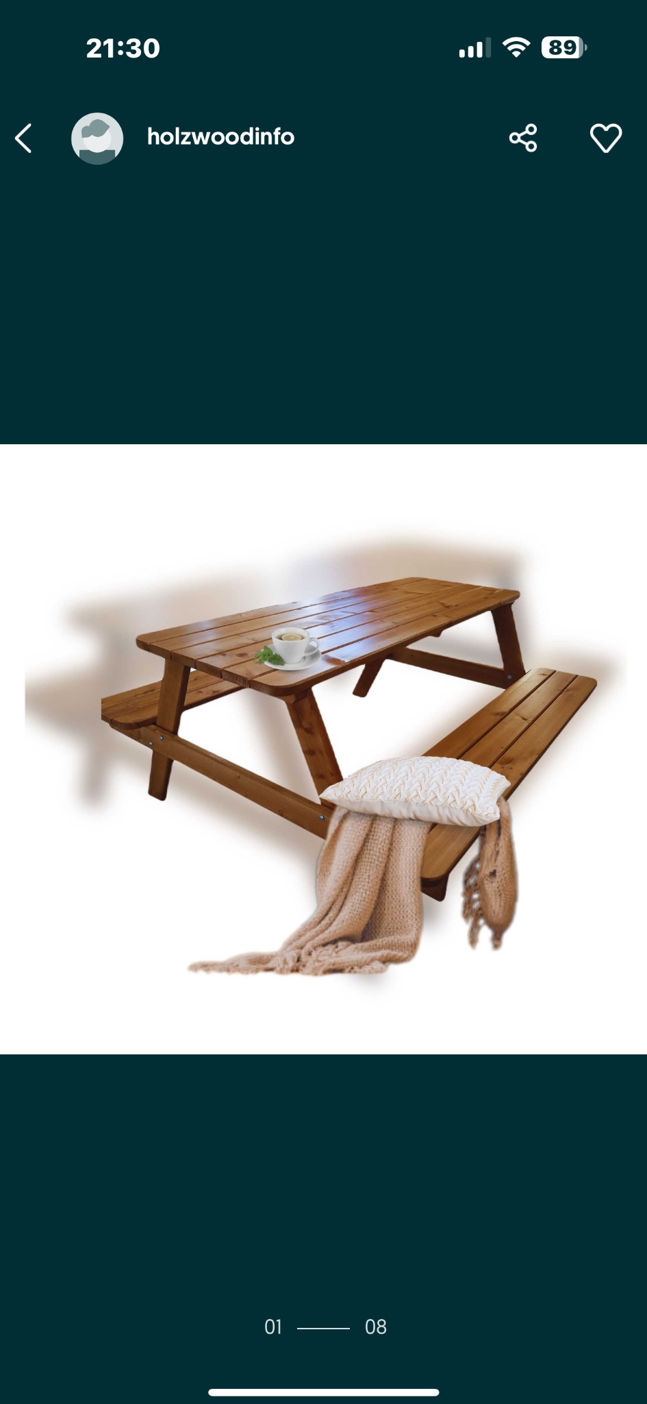 Drewniany stół piknikowy z ławkami, na jednej ławce poduszka i pled w kolorze beżowym, na blacie filiżanka. Jasne tło, ciepłe oświetlenie.