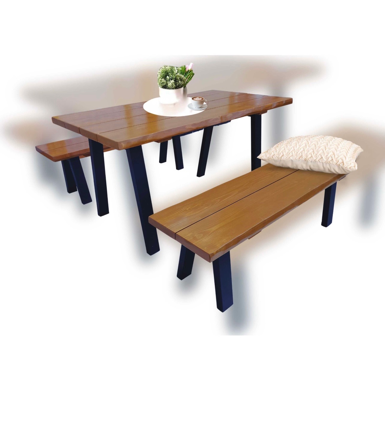 Drewniany stół z ławkami na czarnych nogach. Na stole wazon z kwiatami i filiżanka kawy. Na ławce poduszka. Całość w jasnej tonacji, na jednolitym tle.