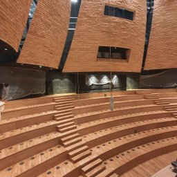 WIESŁAW OPIELA-PARKIETY.PL - Montaż drewnianych schodów amfiteatralnych w sali koncertowej, widok z góry. Wykończenie ścian i sufitu drewnianymi panelami akustycznymi.