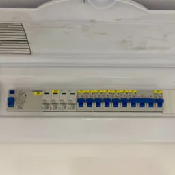 Rozdzielnica natynkowa Schrack z wyłącznikiem RCD i zabezpieczeniami obwodów, estetycznie oznaczona, widoczne gniazda, oświetlenie, urządzenia kuchenne.