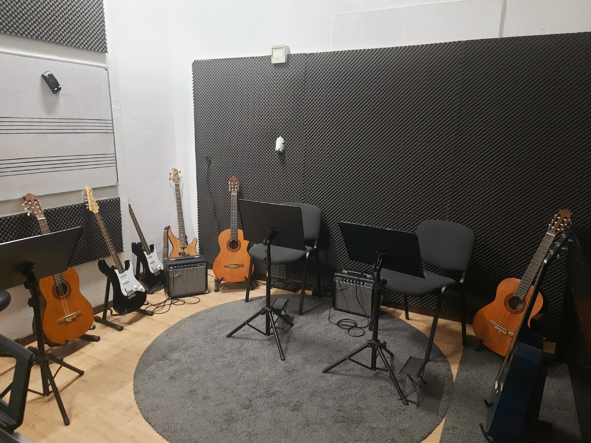 Studio muzyczne w Słupsku z gitarami akustycznymi i elektrycznymi, wzmacniaczami, pulpitami na nuty. Wykładzina tłumiąca dźwięk na ścianach.