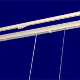 Mechanizm łańcuszkowy do rolety rzymskiej: biała szyna z linkami i łańcuszkiem na ciemnoniebieskim tle, widok z dołu.